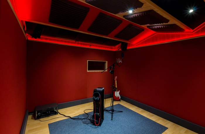 Cabine d’enregistrement avec traitement acoustique, microphone et instruments, pensée pour une prise de son précise, naturelle et adaptée à l’intention sonore du projet.